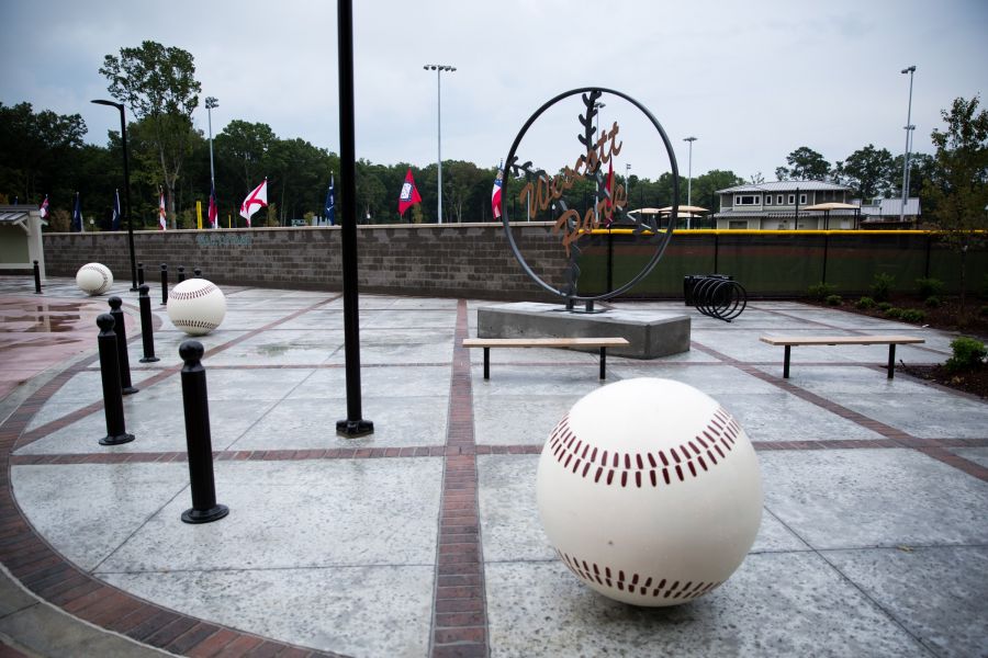 Cedar Grove Outdoor plaza with large baseball sculptures, benches, and a circular “Westcott Park” metal sign in the background.