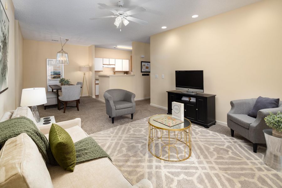 Cedar Grove apartment homes with Modern living room with beige walls, cozy seating, a TV, and a view of the dining area and kitchen in back.
