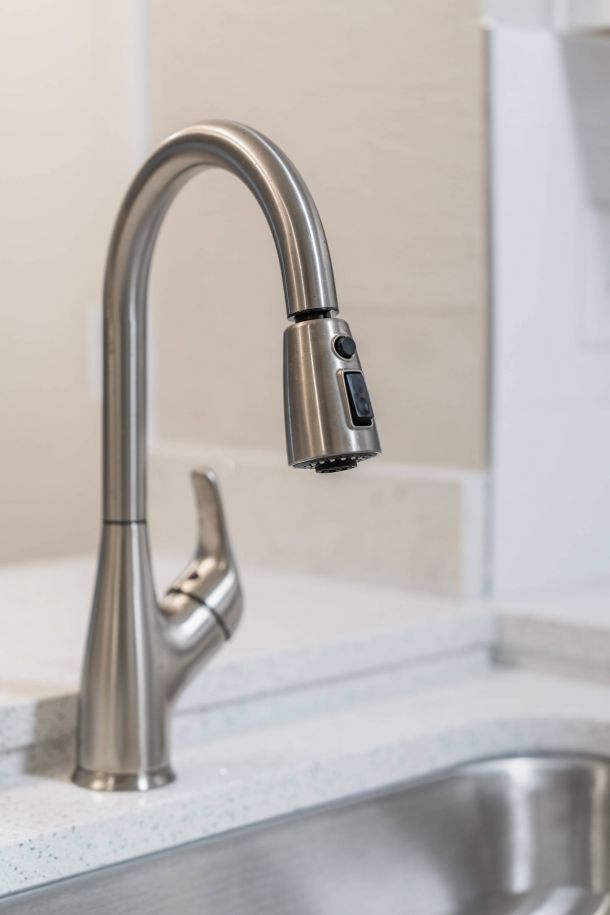 Attain on 5th apartment homes with Modern stainless steel kitchen faucet with a curved neck and a pull-down spray head above a sink.