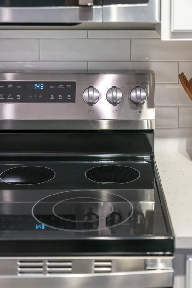 Cedar Grove Stainless steel electric stove with four burners and digital clock showing 1:43 in a modern kitchen.