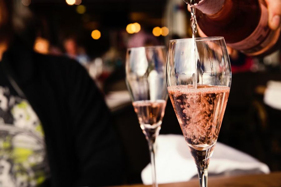 Cedar Grove Sparkling rosé wine being poured into a glass at a restaurant, with another filled glass nearby.