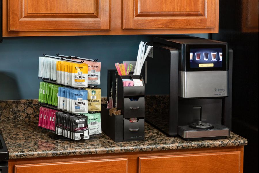 Cedar Grove apartment homes with Coffee machine on a counter with stacked drink packets, stirrers, and straws beside it.