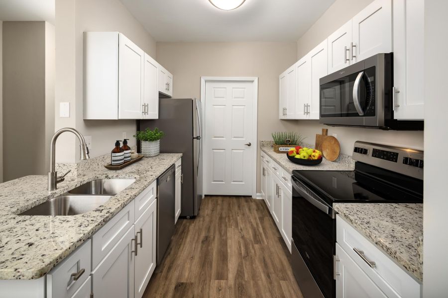 Cedar Grove apartment homes with Modern kitchen with white cabinets, granite countertops, stainless steel appliances, and wood flooring.