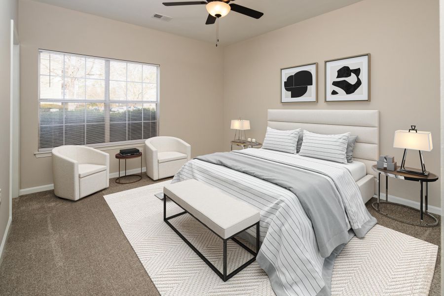 Cedar Grove apartment homes with Modern bedroom with a neatly made bed, two armchairs, large window, and minimalist decor.