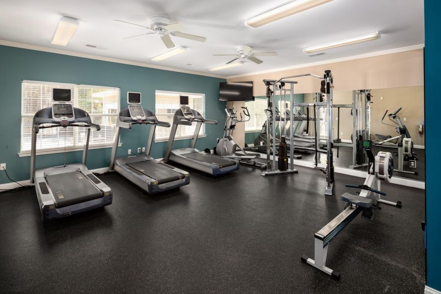 Cedar Grove apartment homes with Small gym with treadmills, ellipticals, weight machines, rowing machine, mirrors, and windows with natural light.