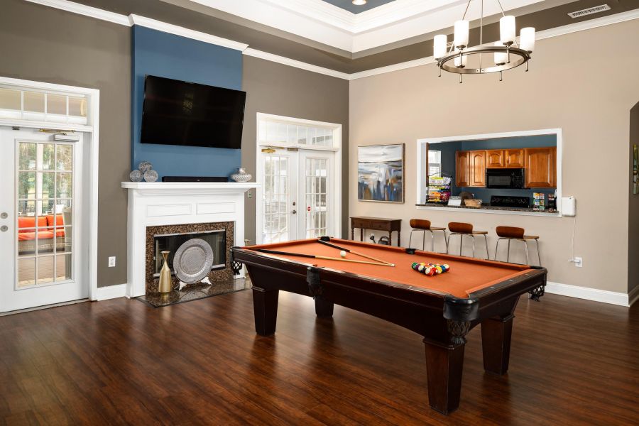 Cedar Grove apartment homes with A billiards table in a modern lounge with a TV, fireplace, and kitchen area in the background.